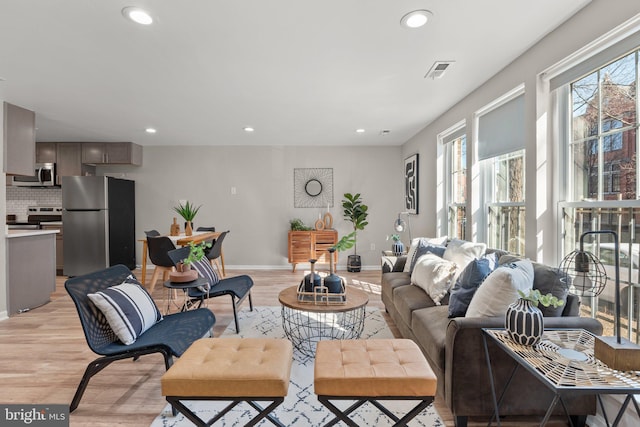 living room featuring light wood-type flooring, baseboards, and recessed lighting