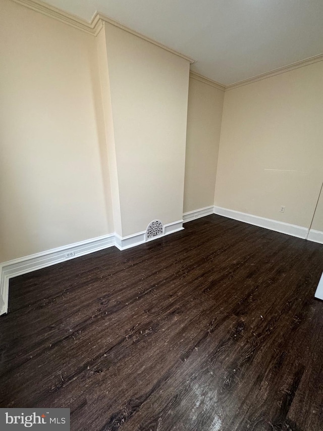 spare room featuring dark wood-style floors, baseboards, visible vents, and crown molding