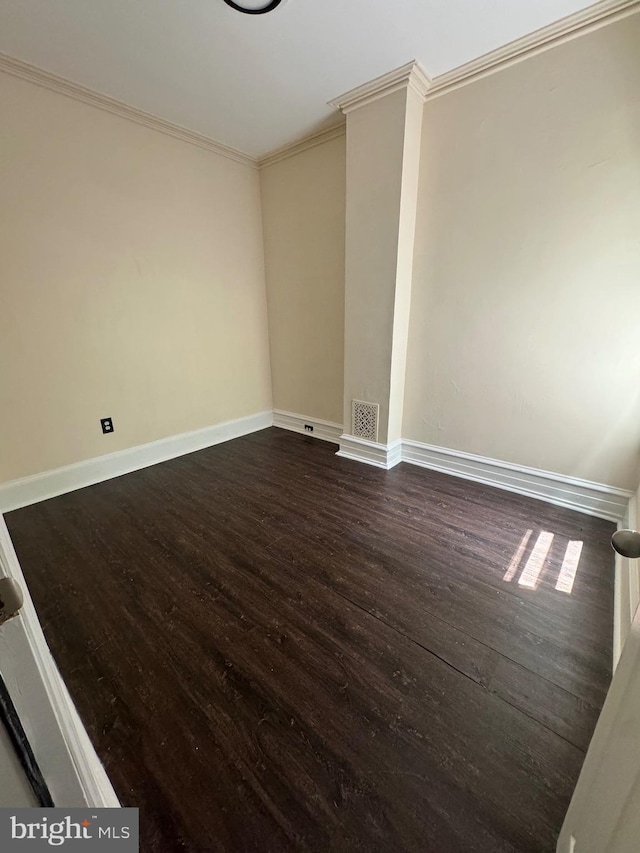 spare room with baseboards, dark wood-type flooring, visible vents, and crown molding