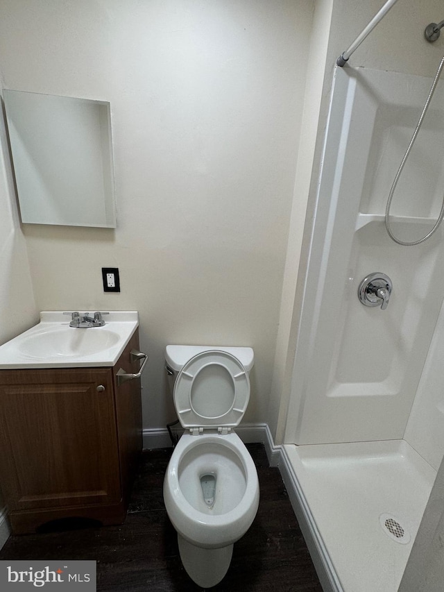 bathroom featuring a stall shower, baseboards, wood finished floors, and vanity