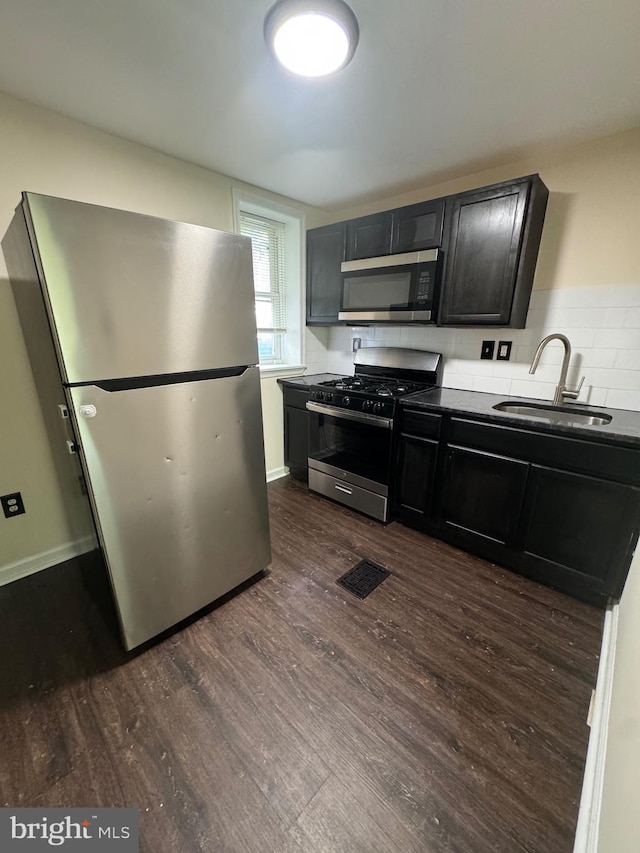 kitchen featuring dark countertops, visible vents, appliances with stainless steel finishes, dark wood-type flooring, and a sink