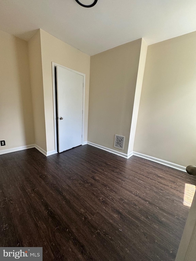 unfurnished room featuring dark wood-style floors, baseboards, and visible vents