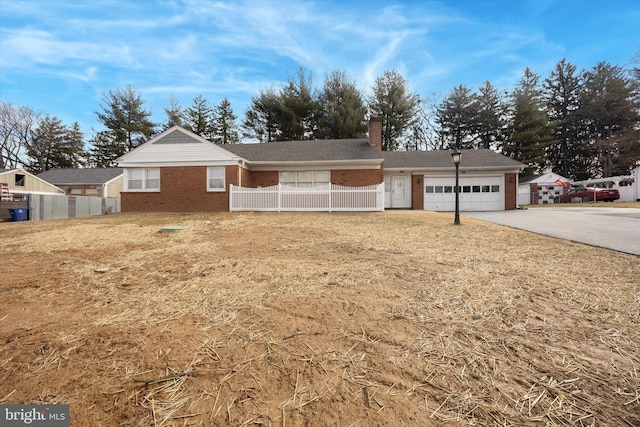 ranch-style home featuring fence, concrete driveway, a garage, brick siding, and a chimney