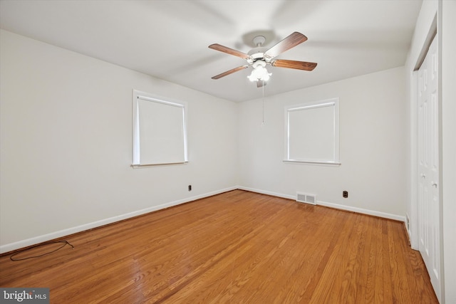 unfurnished bedroom with wood finished floors, visible vents, a closet, and baseboards