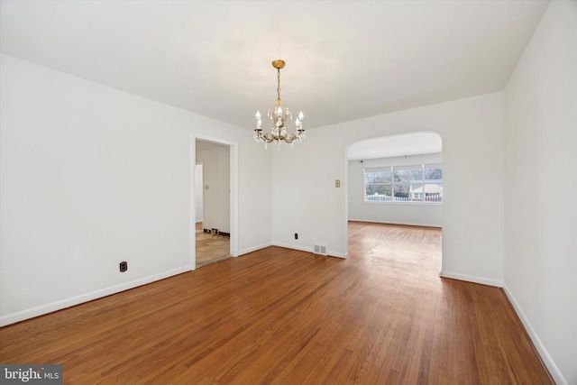 interior space featuring arched walkways, visible vents, baseboards, and wood-type flooring