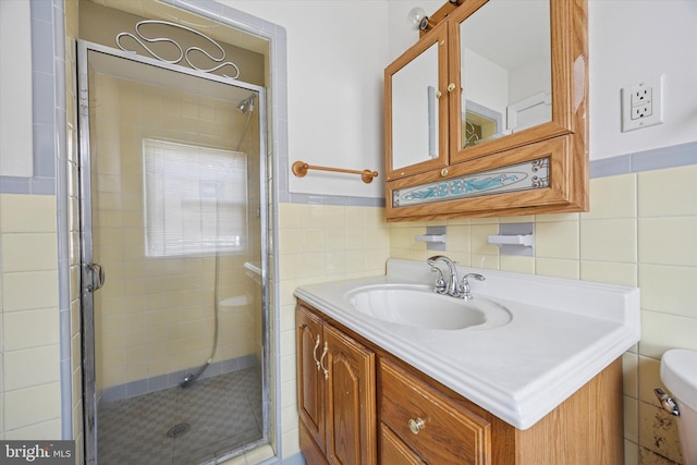 bathroom featuring toilet, tile walls, a stall shower, and vanity