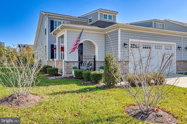 view of front of house featuring driveway, a garage, stone siding, covered porch, and a front yard