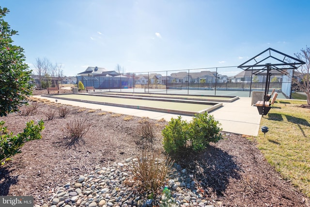 view of community featuring a tennis court, fence, and a residential view