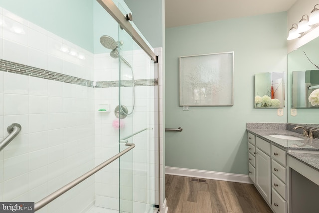 bathroom featuring baseboards, a shower stall, vanity, and wood finished floors