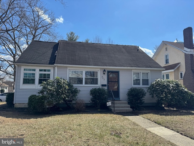 view of front of home featuring a front lawn and roof with shingles