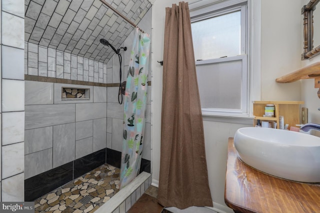 bathroom with tiled shower and a sink