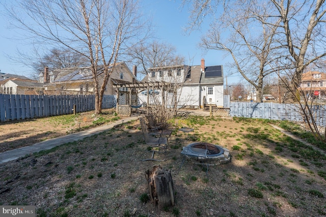 back of house with a chimney, solar panels, a fire pit, and a fenced backyard