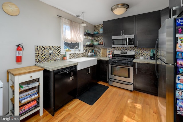 kitchen featuring open shelves, a sink, stainless steel appliances, light countertops, and dark cabinets