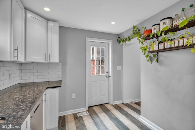 kitchen with baseboards, visible vents, dark wood-type flooring, white cabinetry, and backsplash