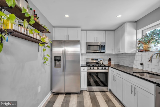 kitchen with a sink, stainless steel appliances, decorative backsplash, and white cabinetry