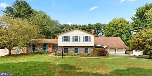 split level home featuring an attached garage, a chimney, and a front yard