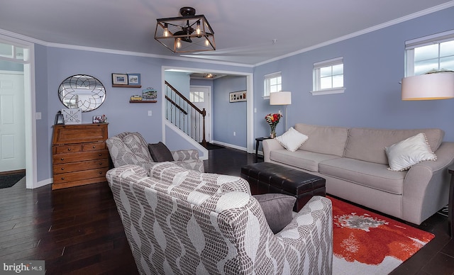 living area featuring dark wood finished floors, baseboards, ornamental molding, and stairs