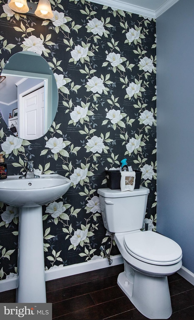 bathroom with toilet, crown molding, baseboards, and wood finished floors