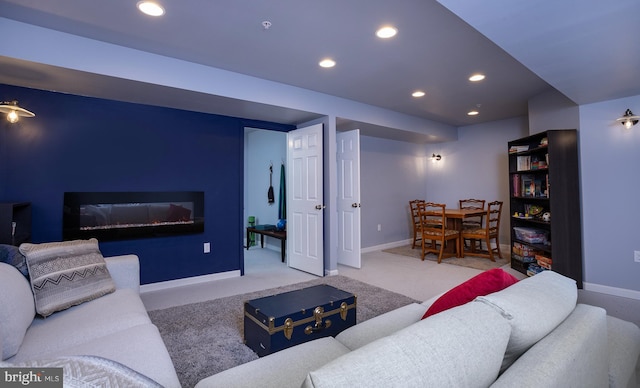 carpeted living room featuring recessed lighting, baseboards, and a glass covered fireplace