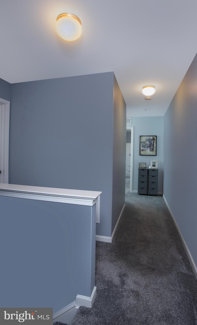 hallway with dark carpet and baseboards