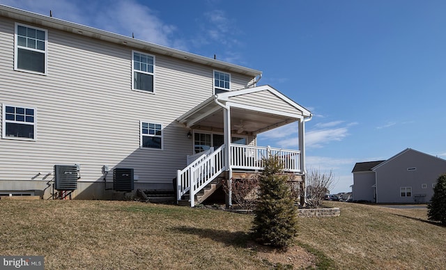 back of property with a yard, central AC, a ceiling fan, and stairway