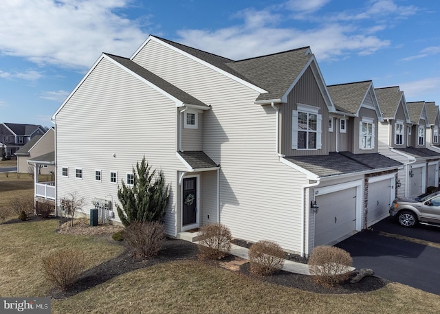 view of front of home featuring aphalt driveway, a garage, a residential view, and a shingled roof