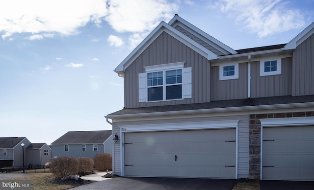 exterior space with an attached garage, board and batten siding, and stone siding