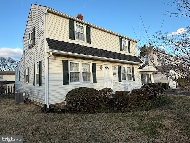 colonial inspired home featuring a front lawn, central AC, a chimney, and a shingled roof