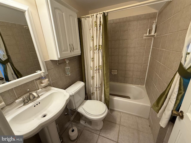 bathroom with a sink, tile patterned flooring, tile walls, toilet, and tasteful backsplash