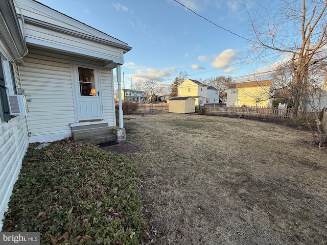 view of yard with an outbuilding, a storage shed, entry steps, and fence