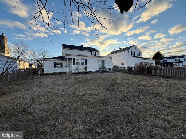 rear view of house with a yard and a fenced backyard