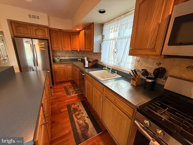 kitchen featuring visible vents, dark wood finished floors, a sink, appliances with stainless steel finishes, and dark countertops