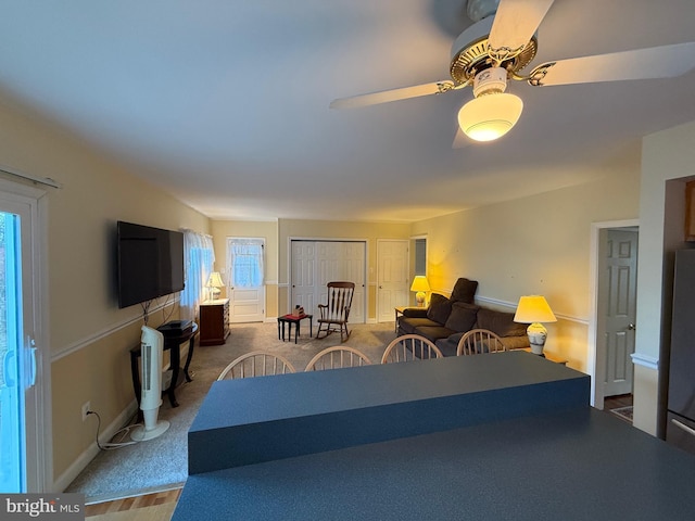 carpeted living area with baseboards and a ceiling fan