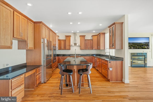 kitchen featuring appliances with stainless steel finishes, recessed lighting, wall chimney range hood, and light wood finished floors