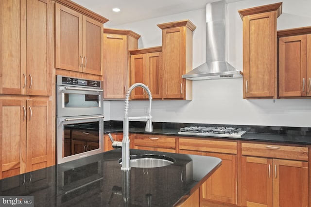 kitchen featuring appliances with stainless steel finishes, recessed lighting, dark stone countertops, and wall chimney exhaust hood