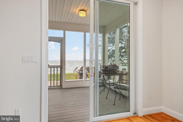 doorway with a water view, baseboards, and wood finished floors