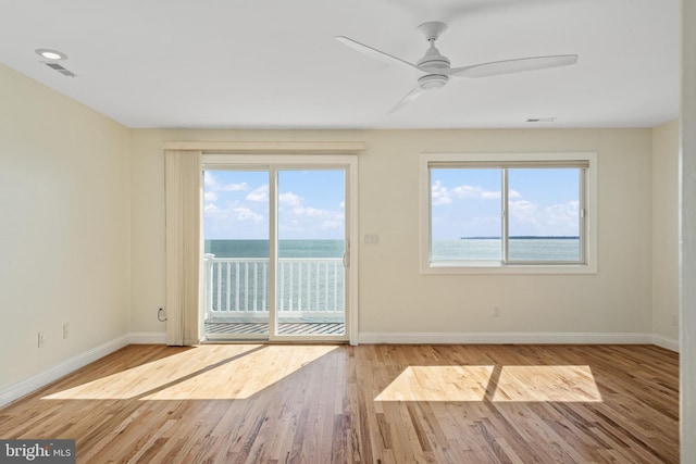 interior space with ceiling fan, plenty of natural light, wood finished floors, and baseboards