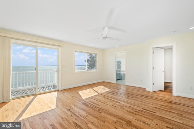 empty room featuring baseboards, ceiling fan, and light wood-style floors