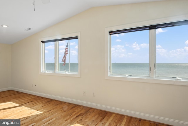 spare room with visible vents, baseboards, vaulted ceiling, and wood finished floors