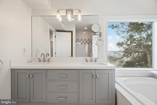 bathroom with double vanity, tiled bath, and a sink