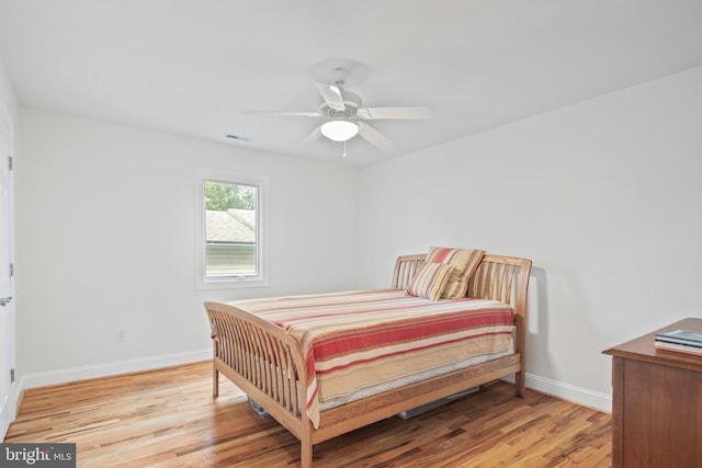 bedroom with baseboards, ceiling fan, visible vents, and light wood-style floors