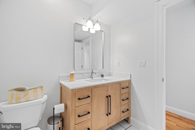 half bath featuring toilet, baseboards, a notable chandelier, and vanity