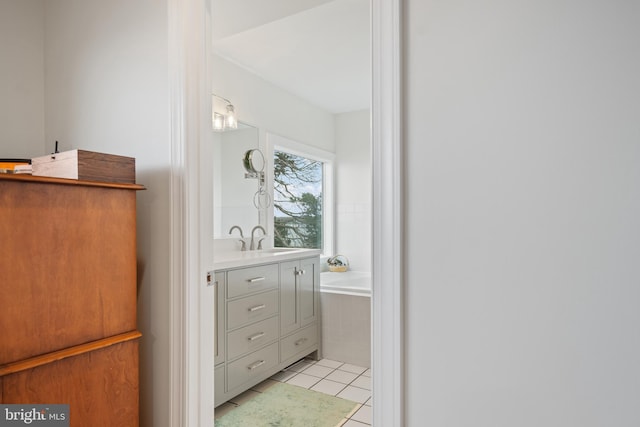 full bath featuring tiled tub, vanity, and tile patterned floors