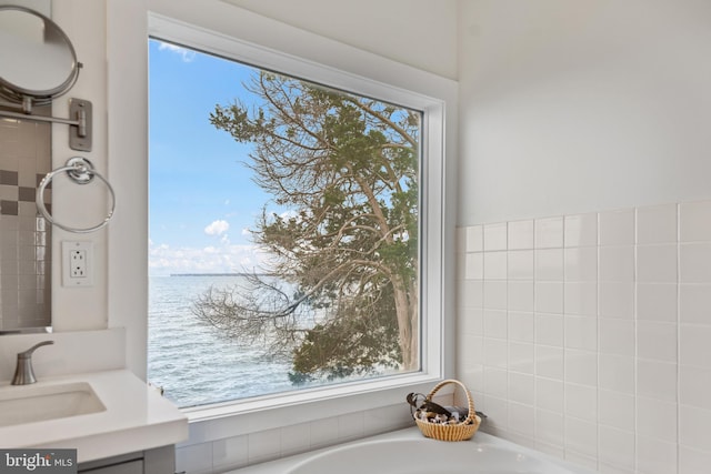 bathroom with a water view, vanity, and a bath