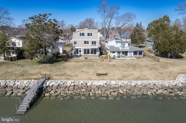 rear view of house featuring a water view, a lawn, a gambrel roof, fence, and a residential view