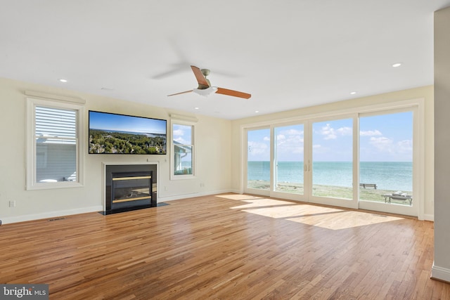 unfurnished living room with a fireplace with flush hearth, recessed lighting, wood finished floors, and baseboards