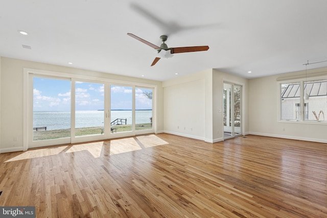 unfurnished living room with a wealth of natural light, light wood-type flooring, and baseboards