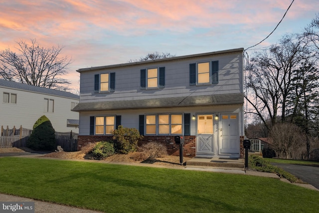 view of front of house featuring a yard, fence, and brick siding