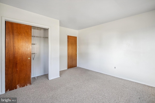 unfurnished bedroom with a closet, baseboards, and carpet flooring