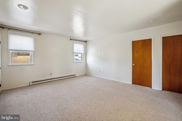 empty room featuring baseboard heating and carpet